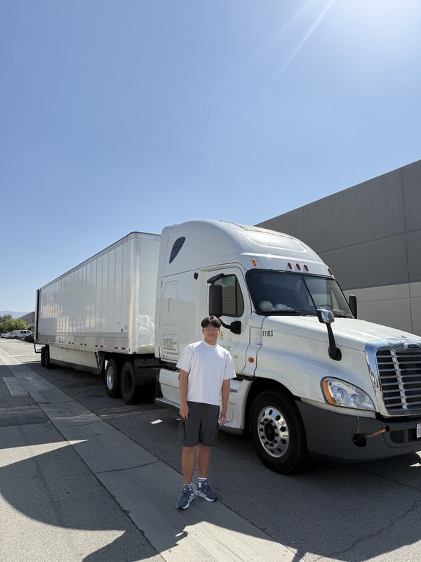 Ashton Jung standing beside a loaded semi-trailer during the Braille Institute delivery