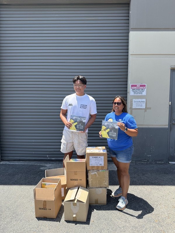 Ashton Jung and a partner with stacked boxes of Braille books at the Orange County United Way delivery